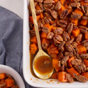 candied sweet potato es in casserole with serving spoon.