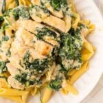 Chicken Florentine served over pasta on a plate.