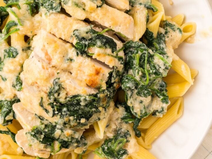 Chicken Florentine served over pasta on a plate.