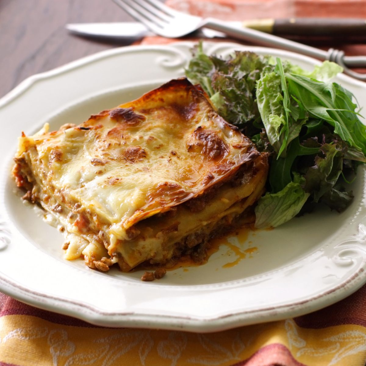 Image of slice of lasagna on a plate with a salad.