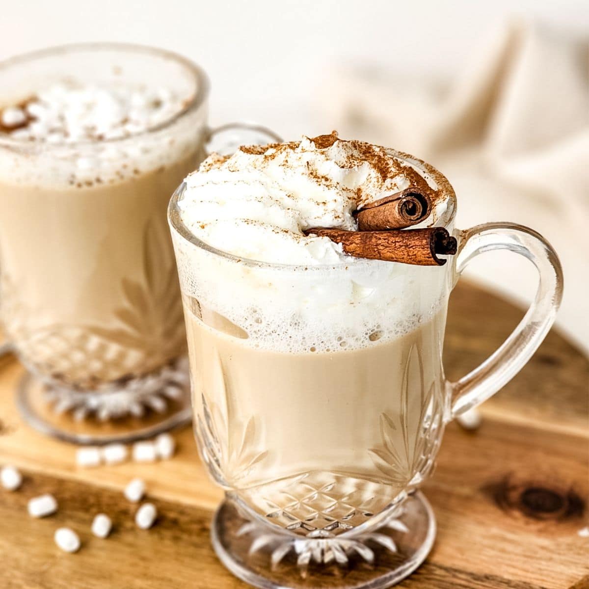 Eggnog latte in a glass mug garnished with whipped cream.