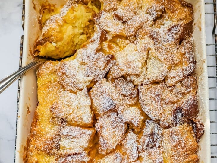 Easy Bread Pudding in baking dish with scoop being lifted out.
