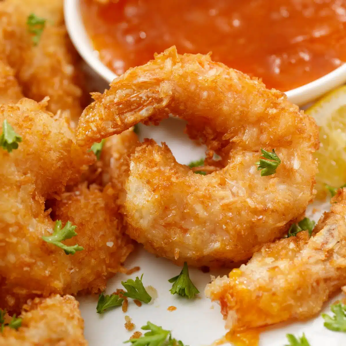 Air-fryer coconut shrimp on plate with dipping sauce.