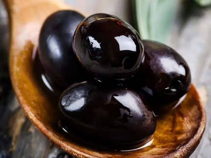 Wooden spoon with black olives.