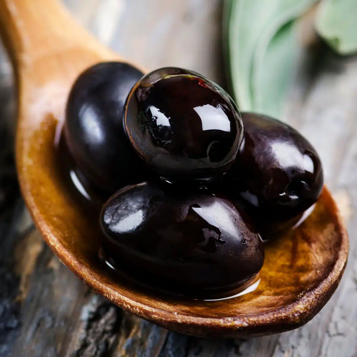 Wooden spoon with black olives. 
