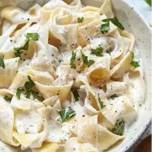 Cottage cheese alfredo sauce over fettuccine pasta in bowl.