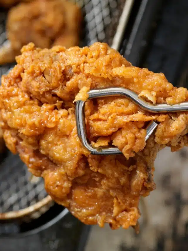 Fried chicken piece being held with tongs.