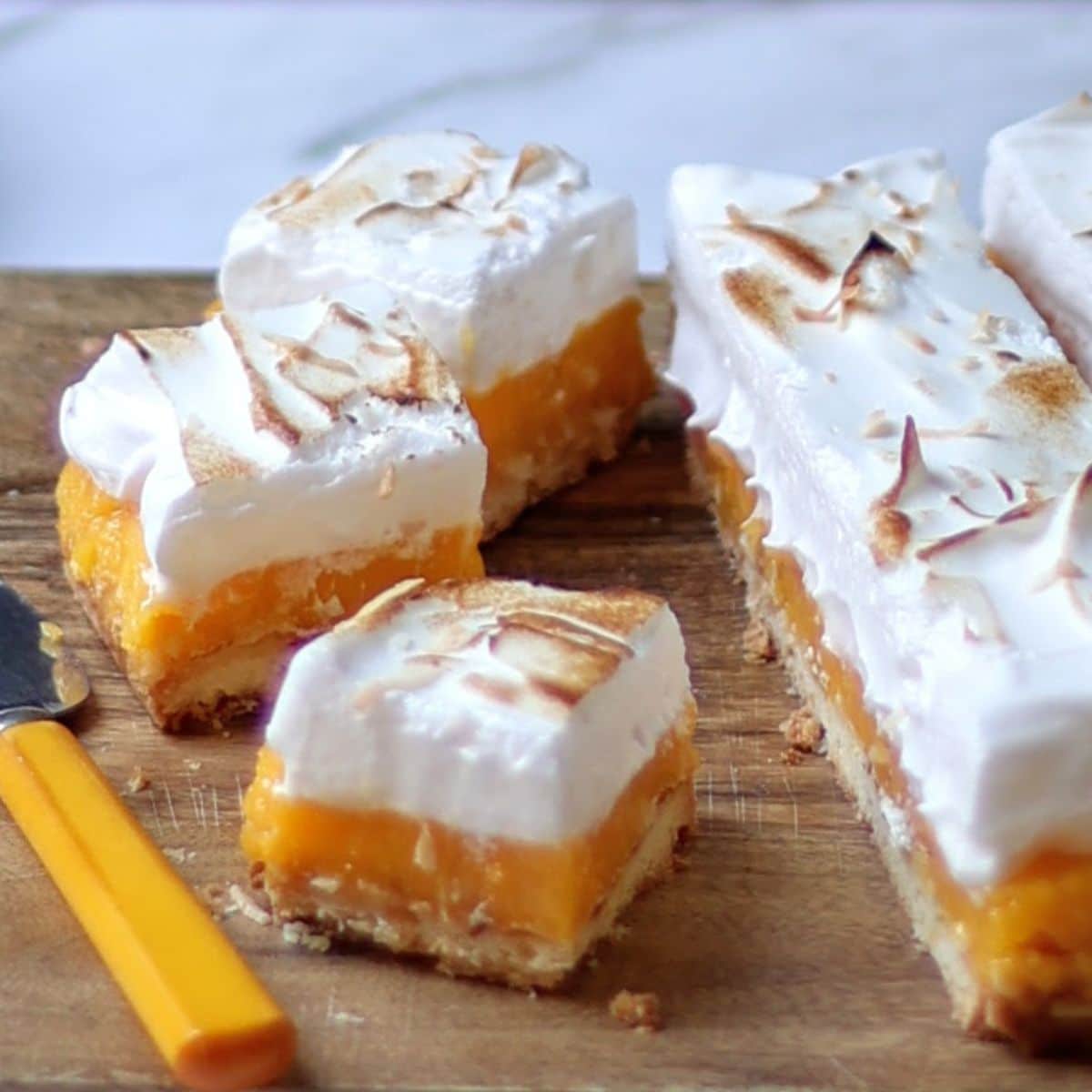 lemon meringue bars being cut on a board.
