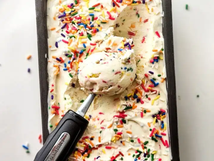 Birthday cake ice cream in a loaf pan with a ice cream scoop.