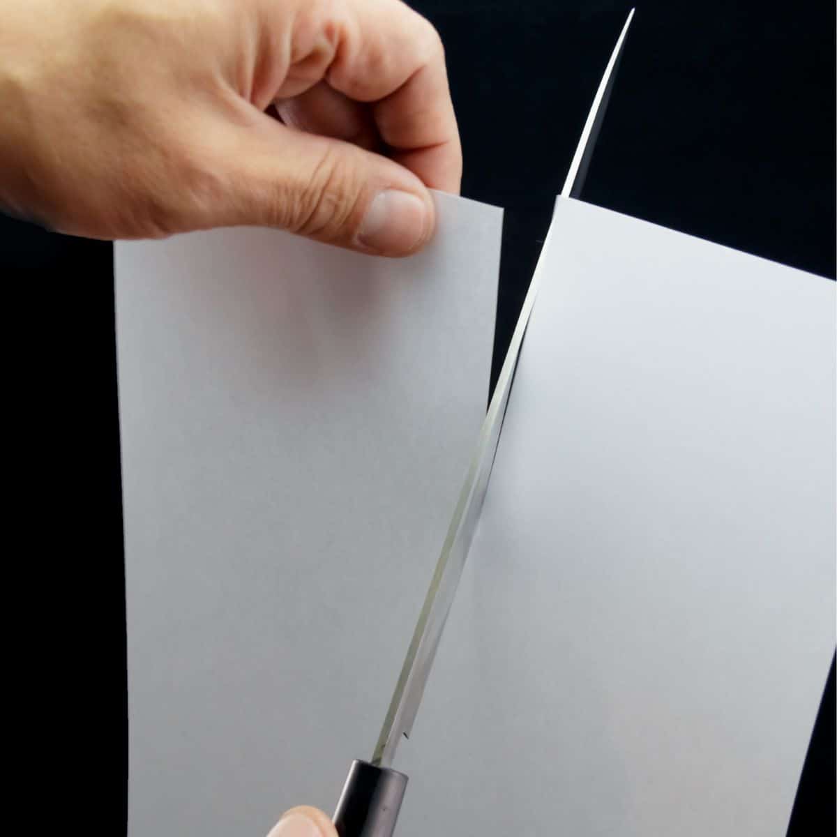 Knife cutting through a sheet of paper.