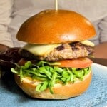 Grilled burger with cheese, tomato and arugula on a bun.