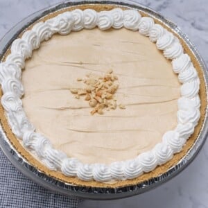 Dolly Parton'e Peanut Butter Pie garnished with whipped cream and peanuts.