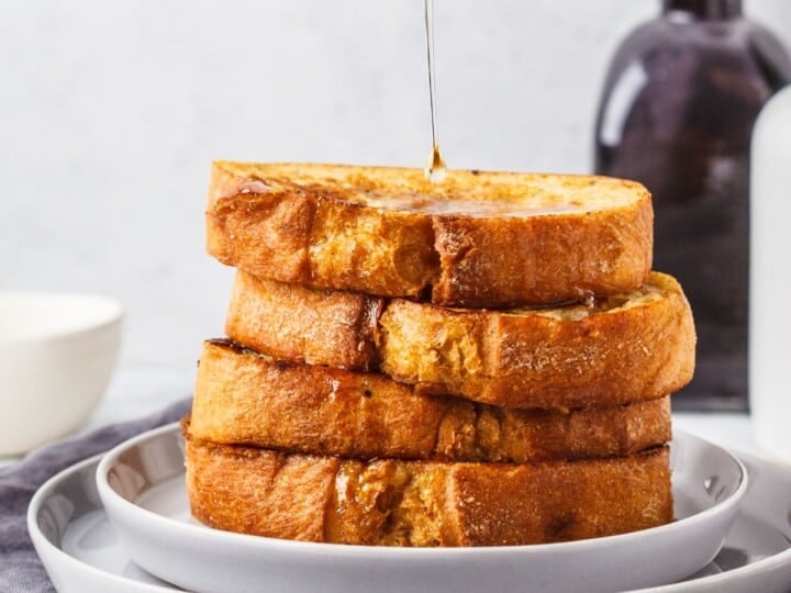 Stack of French toast being drizzle with syrup.