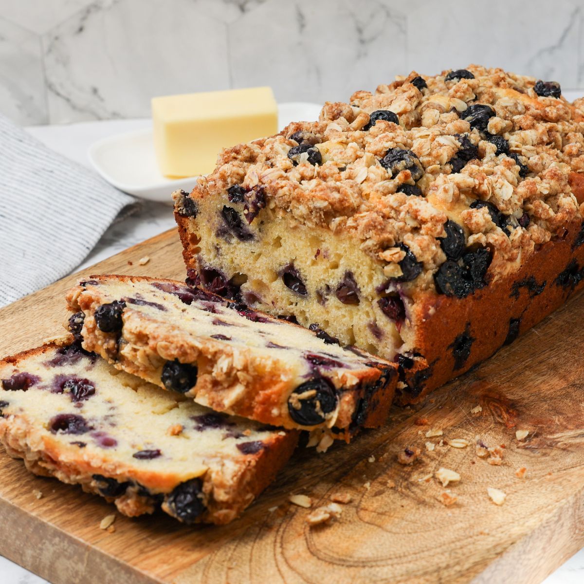Loaf of blueberry muffin bread with slices on a cutting board. 